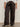 A person wearing Sanctuary Clothing's modern satin trouser in black (extended sizing), paired with a white button-up shirt and black pointed-toe heels, stands against a plain background.