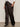 A person stands against a plain background, shown from the shoulders down, wearing Sanctuary Clothing's modern satin trouser in black extended sizing, paired with a white rolled-sleeve shirt and black pointed-toe heeled boots.