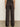 A person faces away from the camera, wearing Sanctuary Clothing„¢s modern satin trouser in black, featuring back pockets, against a plain light wall and concrete floor.