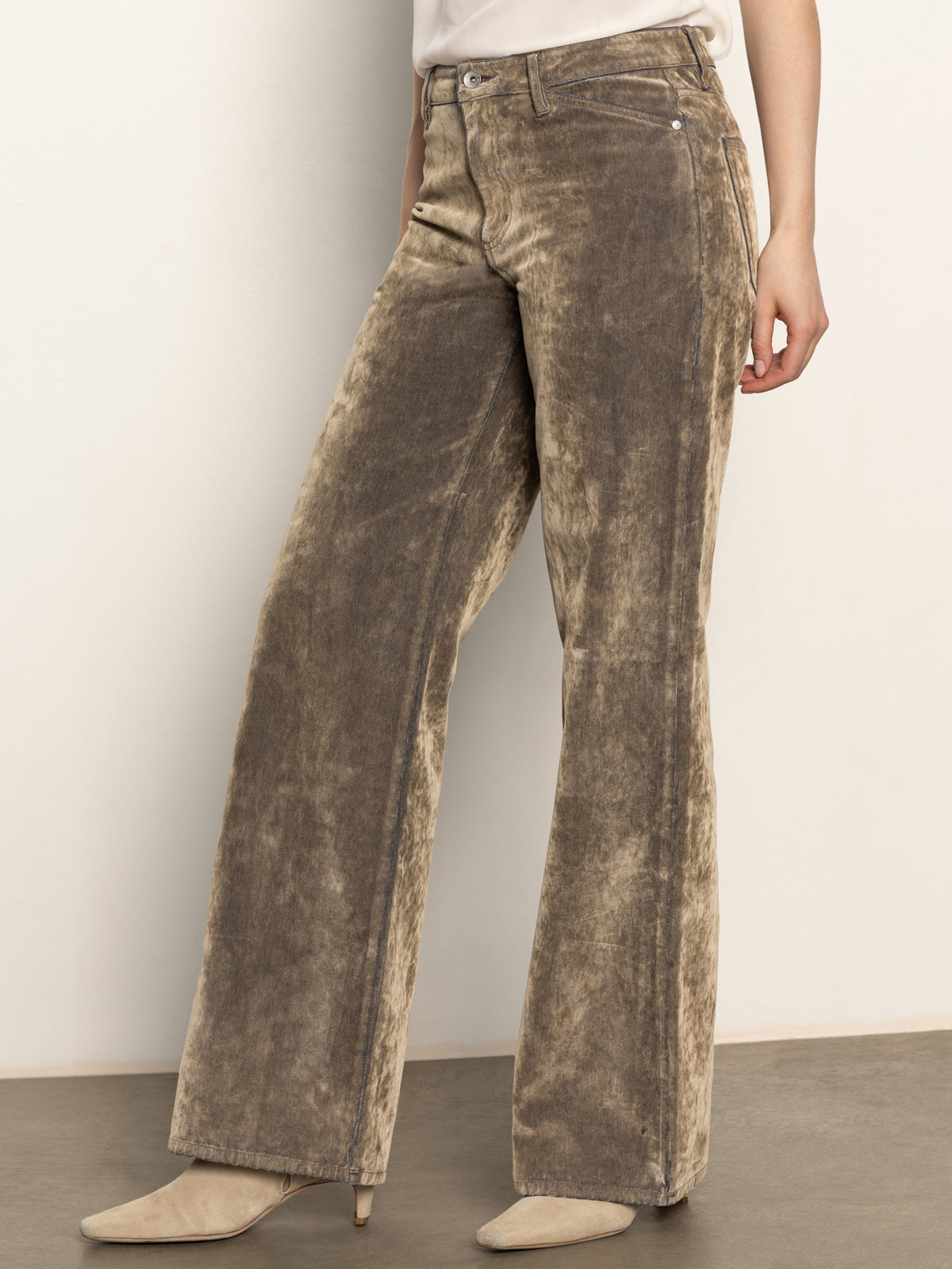 Wearing Sanctuary Clothing’s cadence relaxed straight jean in light bronze with light beige pointed-toe shoes, standing against a plain off-white wall; upper body partially out of frame.