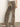 Wearing Sanctuary Clothing’s cadence relaxed straight jean in light bronze with light beige pointed-toe shoes, standing against a plain off-white wall; upper body partially out of frame.