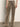 A person stands with their back to the camera, wearing Sanctuary Clothing's cadence relaxed straight jean in light bronze, paired with beige heeled shoes against a plain background.