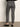 A person is seen from behind wearing Sanctuary Clothing's 90s straight legging burnt olive plaid petites, featuring a high-waisted, slim-fit design in brown, blue, and gray hues, paired with black flats against a plain backdrop.