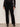 Person wearing black pants and a black top against a white background