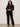 Woman wearing a black outfit against a plain background