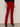 A person wears Sanctuary Clothing's velveteen brook bootcut pant in cherry lacquer (petite), styled with a black long-sleeve top and black heeled ankle boots, standing against a neutral background.