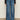 A person wears the Sanctuary Clothing tuxedo relaxed straight jean flirt€�high-waisted, wide-leg blue jeans with a dark denim side panel€�paired with a black long-sleeve top and black shoes, standing against a neutral background.
