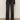A person wearing Sanctuary Clothing's tuxedo relaxed straight jean black tie with a textured black long-sleeve top and heeled boots, standing against a plain light background.