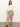 A person stands against a plain background wearing a white blouse with long sleeves and the "All Buttoned Up Skirt" in sage from Sanctuary Clothing. They pair it with brown sandals and pose with one hand on their hip.