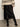Person wearing a patterned sweater, black satin skirt, and black high-heeled boots on a plain background