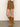 A person wears the Sanctuary Clothing briar corduroy mini skirt in bronze, paired with tan knee-high suede boots. Only the lower half of their body is visible, standing against a plain light wall and concrete floor.