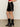 A person wearing Sanctuary Clothing„¢s broadway leather skirt in black with matching black heeled boots stands on a smooth floor, hands in pockets. The upper body is partially visible.
