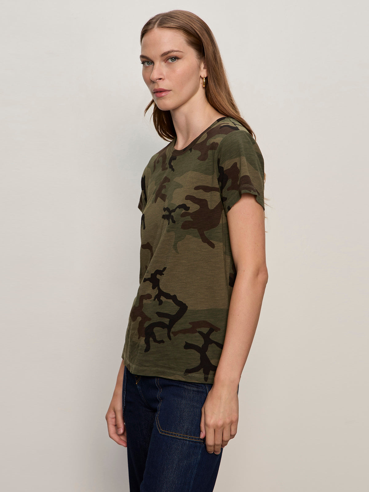 A woman with long, straight hair models the Sanctuary Clothing "the perfect tee hiker camo" t-shirt with dark jeans, standing sideways against a plain light background.