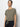 A person with dark hair tied back is wearing a Sanctuary Clothing all day tie tee in trail green and black jeans, standing against a plain white background, looking directly at the camera.