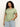A woman with curly hair wears the perfect tee mosaic from Sanctuary Clothing's inclusive collection, paired with blue jeans, against a neutral background. She stands relaxed, her hand in her pocket.