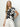 A person with long blonde hair stands against a neutral background, wearing Sanctuary Clothing's "the perfect tee inked impressions" in black and white. They pair it with white pants, accessorize with necklaces, and pose relaxedly with one hand in their pocket.