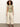 A woman with curly hair wears the perfect tee palm by Sanctuary Clothing, wide-leg cream pants, a brown belt, and brown sandals, standing against an off-white background.