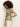 A woman with curly hair stands sideways, wearing Sanctuary Clothing's "the perfect tee palm"—a short-sleeved top with a tropical leaf print—and light pants against a plain, light background.