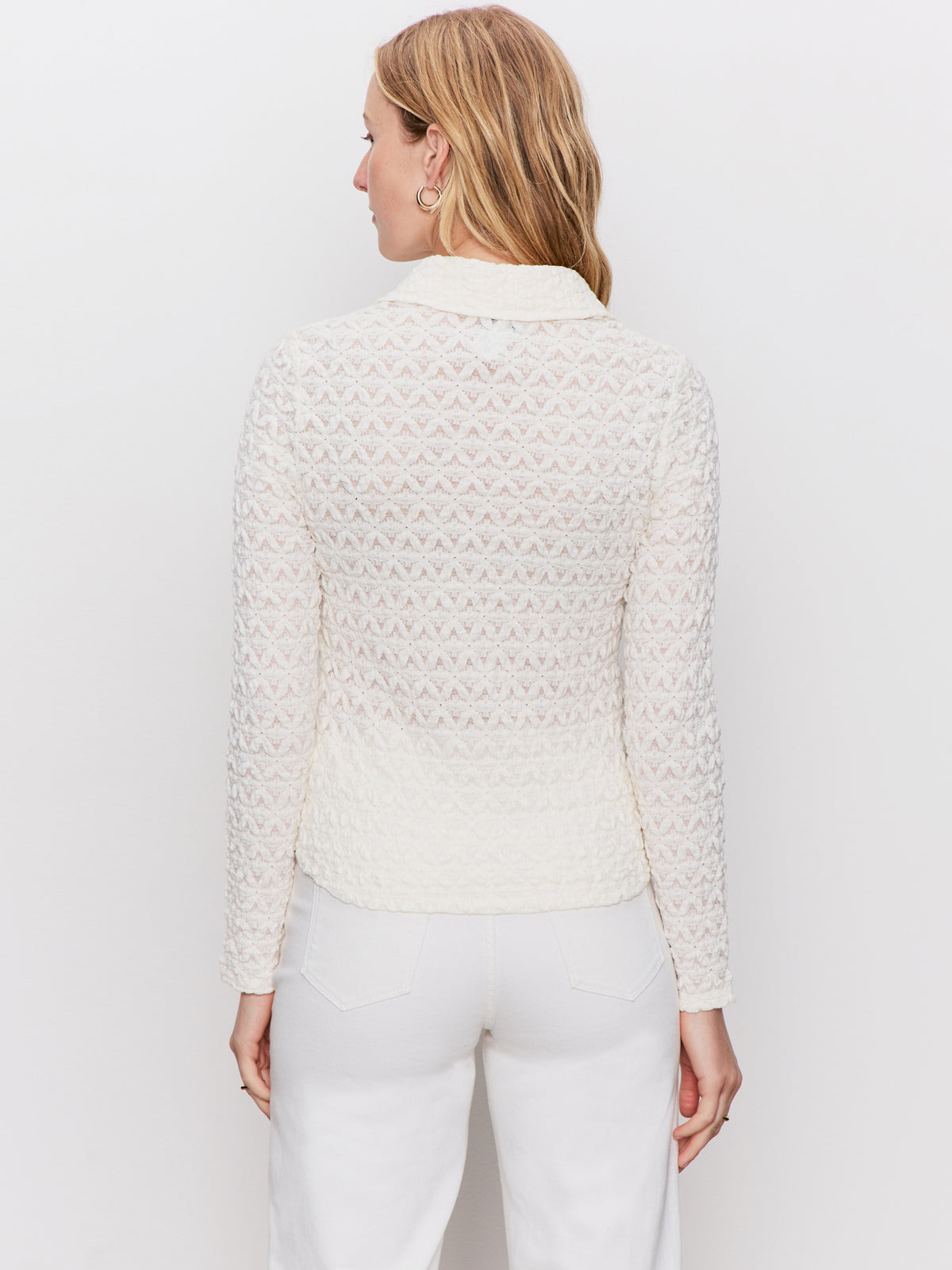 A woman with light brown hair wears the Sanctuary Clothing dreamgirl lace button up chalk and white pants, standing with her back to the camera against a plain white background.