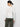 A person with dark hair stands facing away from the camera, dressed in a white long sleeve boatneck t-shirt from Sanctuary Clothing and olive green cargo pants, set against a plain white background.