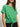 A woman wears the all day eyelet tee palm by Sanctuary Clothing”green with short sleeves and a front tie”paired with black pants. She accessorizes with a gold necklace and hoop earrings, standing against a plain background.