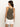A woman with long dark hair stands facing away from the camera, wearing Sanctuary Clothing's ribbed racer tank in kalamata and white shorts against a plain, light background.