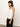 A woman with long brown hair wears a Sanctuary Clothing ribbed racer tank in white paired with black pants, standing against a plain white background and facing slightly to the side.