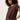 A woman with curly brown hair models the Sanctuary Clothing knotted muscle tee mesa, a short-sleeved, loose-fitting dark brown top styled at the waist, paired with cream pants against a plain light background.