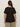 A person with long brown hair wears the Sanctuary Clothing notch neck tee black extended sizing, paired with olive green pants, and stands facing away from the camera against a plain light background.