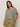A woman with long brown hair models the Sanctuary Clothing notch neck tee light oat black stripe 3, paired with olive green drawstring pants, standing with one hand in her pocket against a plain light background.