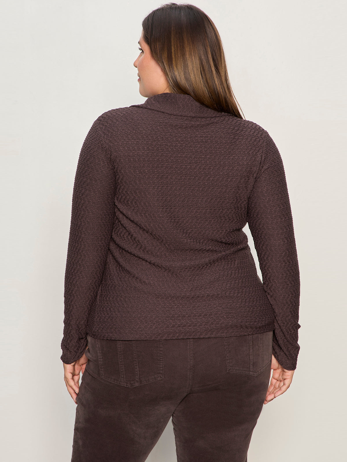 A woman with long brown hair, shown from the back, wears the Sanctuary Clothing textured knit Dreamgirl Top in semi sweet, paired with matching brown pants, standing against a plain light background.