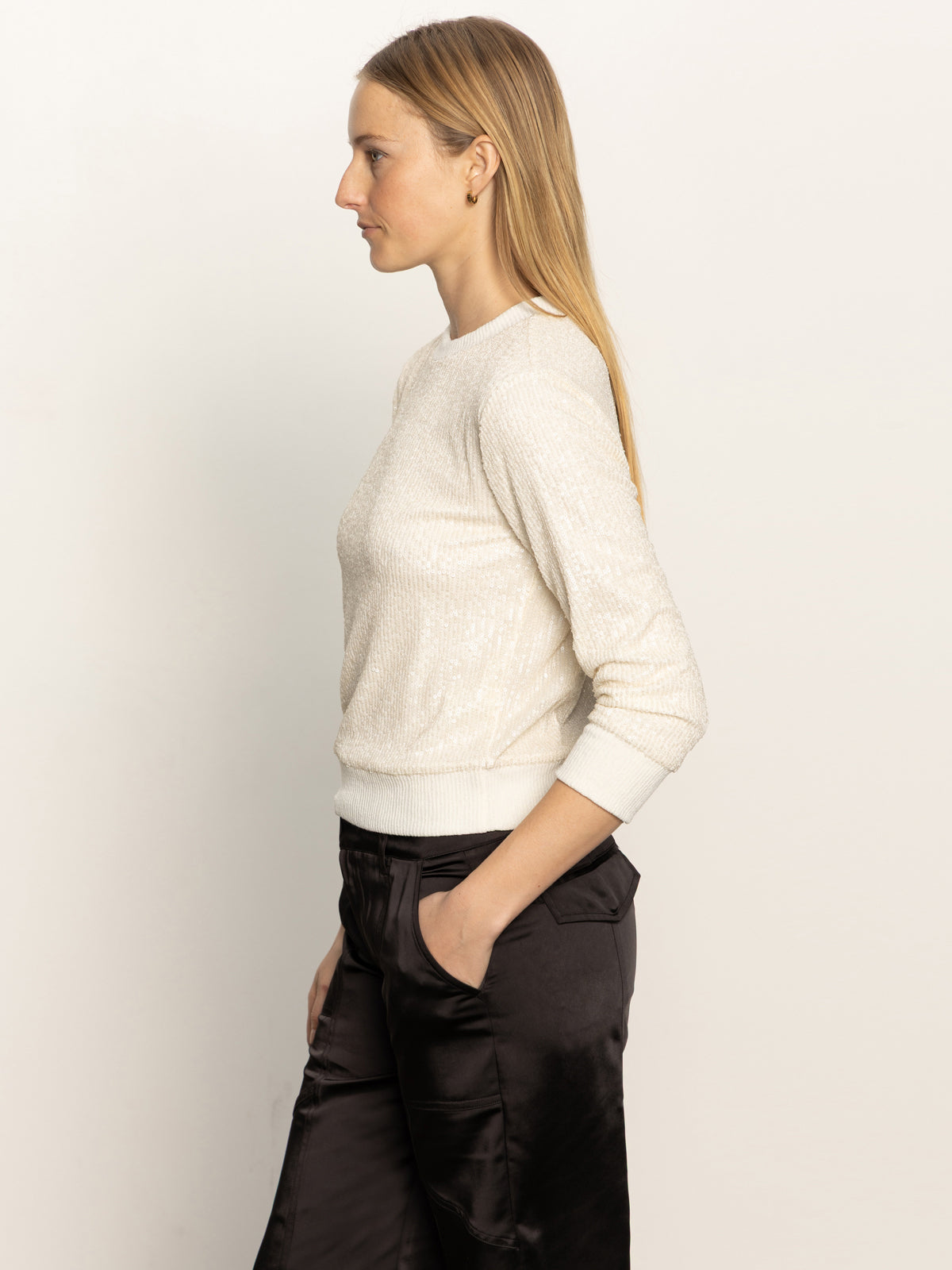 A woman with long blonde hair wears the Sanctuary Clothing relaxed sparkle popover in chalk, standing in profile against a plain light background.