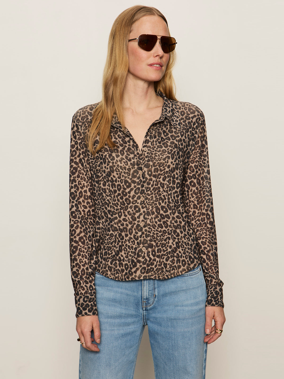 A woman wears the Sanctuary Clothing dreamers top french kitty and light blue jeans, standing against a plain off-white background.