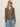 A woman wears the Sanctuary Clothing dreamers top french kitty and light blue jeans, standing against a plain off-white background.