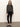 A woman stands indoors against a plain light wall, wearing the Sanctuary Clothing hearthside popover top in heather ink, paired with black leggings and flats. She has long brown hair and a neutral expression.