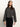 A woman with long brown hair wears the Sanctuary Clothing hearthside popover top in heather ink, a loose-fitting, wide-sleeve dark gray long-sleeve shirt, paired with black pants against a plain light background.