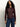 A woman with long curly hair wears the Sanctuary Clothing fitted mesh button down top boheme in maroon and blue jeans, standing against a plain light background.
