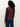 A person with curly hair is shown from the back wearing Sanctuary Clothingžs fitted mesh button down top boheme in maroon, featuring a subtle floral pattern, paired with blue jeans against a plain light background.