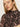 A woman with fair skin and straight blonde hair models the Sanctuary Clothing long sleeve mesh mock top nocturnal, featuring a black and pink pattern, along with small gold hoops against a plain light background.