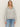 A woman with long blonde hair models the Sanctuary Clothing textured zip up popover in heather grey with light blue jeans, standing against an off-white background and looking at the camera.