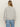A person with long, straight blonde hair is seen from the back wearing Sanctuary Clothing„¢s textured zip up popover in heather grey, styled with light blue jeans against a plain background.