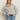 A woman with long blonde hair wears the Sanctuary Clothing textured zip up popover in heather grey and blue jeans, standing with one hand in her pocket against a plain, light background.