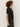 A woman with curly hair stands in profile against a plain background, wearing Sanctuary Clothing's satin mix tee in black and dark gray jeans.