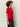 A woman with curly hair stands in profile, wearing Sanctuary Clothing's satin mix tee in cherry lacquer and dark gray jeans against a plain light background.