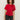 A woman with curly hair wears the Sanctuary Clothing satin mix tee in cherry lacquer, featuring short sleeves and a gathered knot detail, paired with dark jeans against a plain light background.