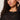 A woman with curly brown hair and gold hoop earrings models the Sanctuary Clothing lovely lace button front top in black extended sizing, featuring sheer horizontal stripes. She poses confidently, raising one hand to her ear.