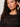 A woman with curly brown hair and gold hoop earrings models the Sanctuary Clothing lovely lace button front top in black extended sizing, featuring sheer horizontal stripes. She poses confidently, raising one hand to her ear.