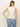 A woman with long hair is facing away from the camera, wearing Sanctuary Clothing's relaxed modern vest in natural metallic stripes, paired with light blue jeans.