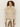 A woman with curly hair wears the Sanctuary Clothing silky fur vest in almond cream (petite sizing) over a sheer, long-sleeved lace top and metallic gold pants, standing against a plain light background.