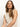 A person with long brown hair poses against a plain background in an open stitch shell sweater eco natural by Sanctuary Clothing. Their sleeveless white knitted top complements their neutral expression, and their head is slightly tilted with hair cascading over their shoulders.